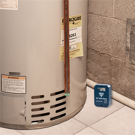 Water heater with a water alarm device on the floor next to it.