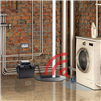 Washing machine in a room with brick walls and a window.