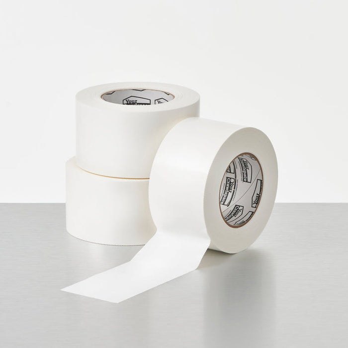 Two rolls of white tape on a light gray surface with a white background