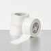 Two rolls of white tape on a light gray surface with a white background